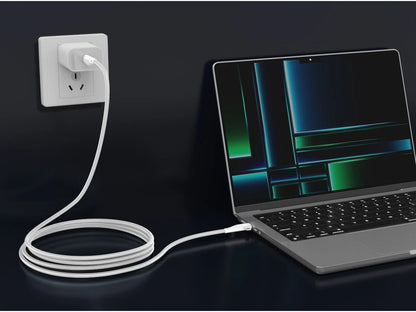 Laptop connected to a power outlet with a white cable on a dark background