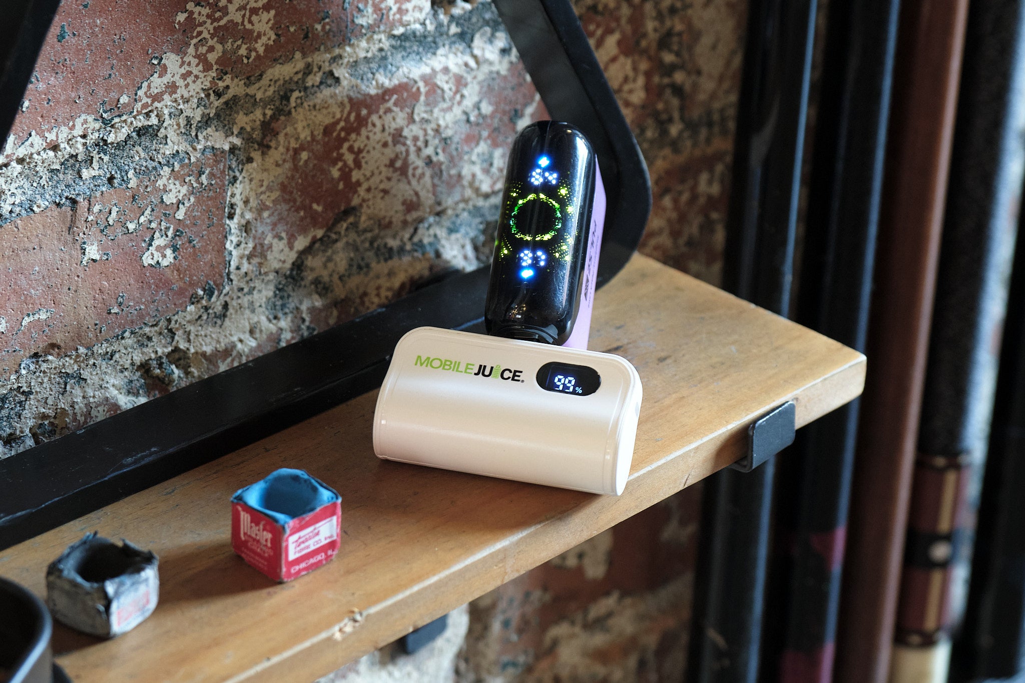 Small electronic device on a wooden shelf with a brick wall background