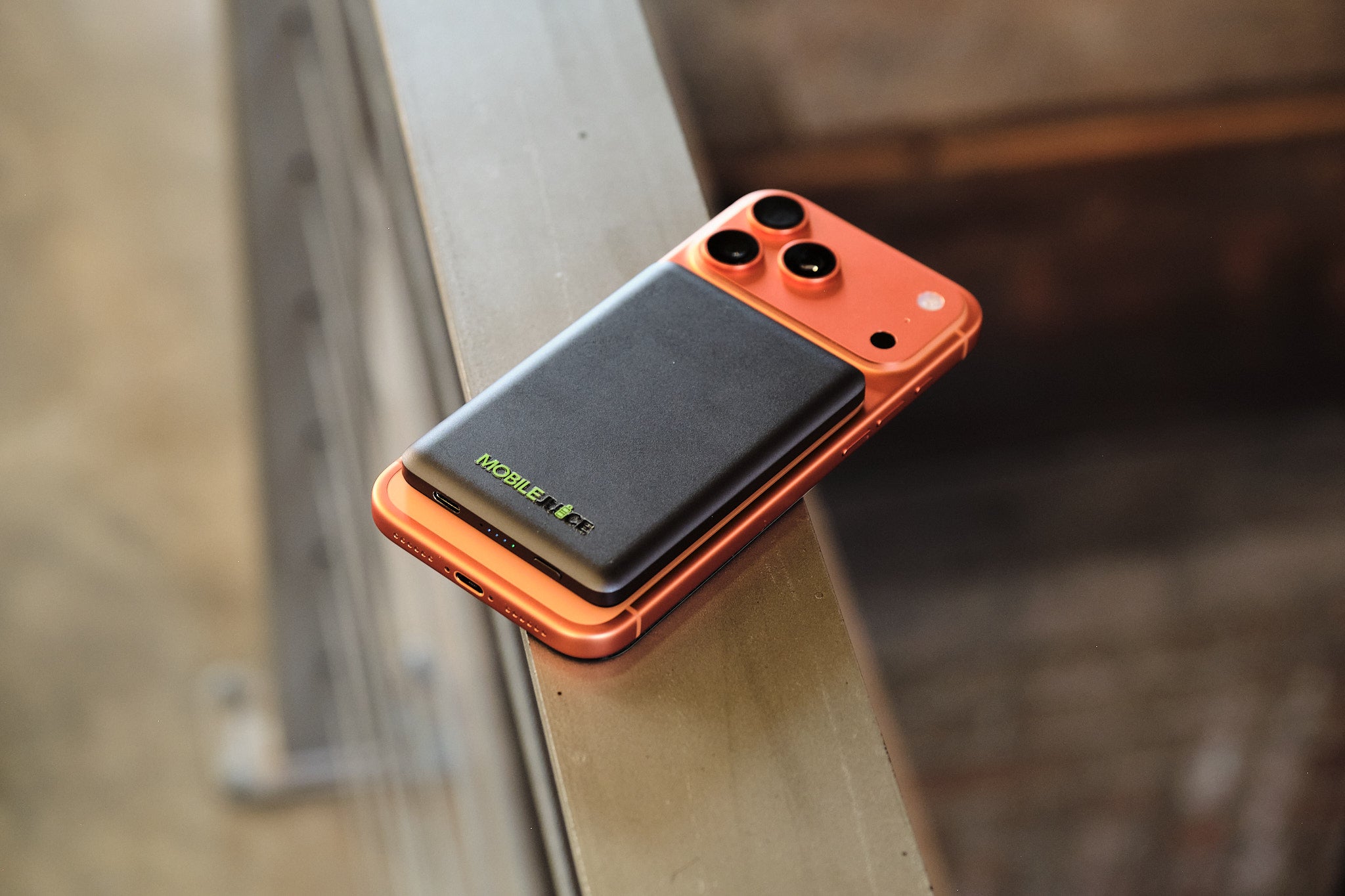 Orange smartphone with black back on a metallic surface
